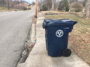 Photo shows proper way to place city garbage cans by the streets with lids firmly closed and wheels facing away from the road