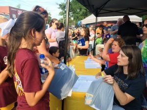 DeKalb West School teachers passing out school supplies to students during Education Celebration downtown last year