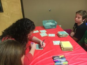 Kids and other volunteers decorate a quilt square during regifting event