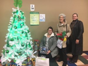 Three generations: Jeanette Smithson (center), daughter Pamela Hale (right), and granddaughter Jessica Hale (left) bring gifts in support of Foster Children during Monday’s “Festival of Trees” at the County Complex. They placed their gifts under the 4-H Club tree