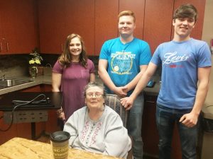 NHC resident Beverly Cripps receives a charging station to keep near her bed for maintaining power to her phone and other electronics made by DCHS students Haley Chapman, Garrett Driver, and Noah Johnson through the STEM Technology and CTE programs in partnership with NHC Health Care Center of Smithville