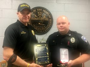 Smithville Police Chief Mark Collins presents plaque for bravery and medal badge to Officer Andy Snow