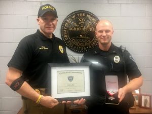 Smithville Police Chief Mark Collins presents Commendation Certificate and medal badge to Officer Will Judkins