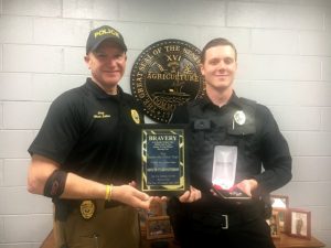 Smithville Police Chief Mark Collins presents plaque for bravery and medal badge to Officer Tyler Patterson
