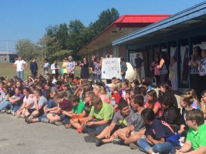 DeKalb Middle School students listen and display "Welcome Back" banner as US Army Guard Sergeant Jake Merriman addresses them after his arrival. He returned home Wednesday after a 10 month deployment in Iraq