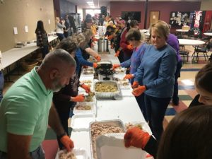 Volunteers filling food trays at their assigned places in preparation for delivery to the needy on Thanksgiving Day