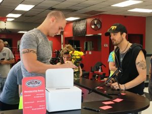 Bobby Johnson, owner of Gym Bob's Fitness Center signing up new member during Saturday's Grand Opening