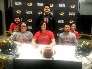 DCHS Quarterback Axel Aldino signed with the University of Central Missouri at Warrensburg, Missouri to play quarterback and major in business marketing. He was joined at the announcement by members of his family: Seated left to right: Cecilin Aldino (mother), Axel Aldino, and Omar Aldino (father). Standing left to right: Jerusalem Aldino (sister), Omar Aldino (brother), and Emilet Aldino (sister)