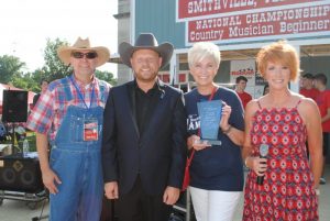 Jamie Dailey received the Fiddlers’ Jamboree’s 2021 Blue Blaze Award Saturday., July 3. Making the presentation were Jamboree President and Coordinator Sam Stout, Chamber President Suzanne Williams, and Jamboree Marketing Director Shan Stout