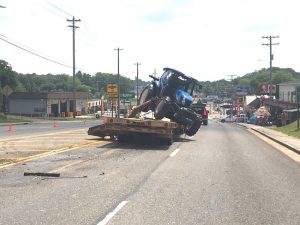 An accident occurred Monday morning on Broad Street as an eastbound International semi and trailer, driven by 60 year old Ronald Moon of Crossville, went under the South College Street (Veterans Memorial) bridge while hauling a New Holland tractor and bush hog. The extended arm and box blade of the bush hog apparently hit the underside of the bridge causing some minor damage to the structure