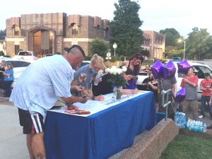 Attendees of Glowstick Vigil signing the Blessing Banner in tribute to victims and survivors of drug overdose