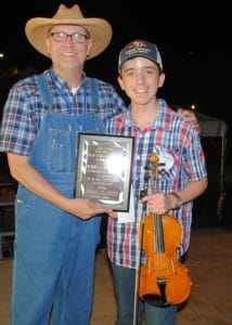 13 year old Noah Goebel claimed the Grand Champion Fiddling Title at the 51st edition of the Smithville Fiddlers Jamboree and Crafts Festival. Sam Stout, President and Coordinator of the Fiddlers Jamboree presented the award to Goebel at the conclusion of the festival which ended at 11: 30 p.m. Saturday evening, July 2