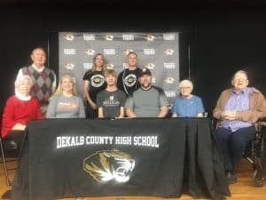 Friends, family, and coaches joined DCHS Senior Aaron Gottlied Friday, January 27 at the school as the star Cross Country runner signed a letter of intent with Milligan University to join the nationally acclaimed Buffaloes. Pictured seated left to right: Peggy Wood, Carrie Gottlied, Aaron Gottlied, Edward Gottlied, Mary Gottlied, and John Gottlied. Standing left to right: Dennis Wood, Coach Kristen VanVranken and Coach Paris Rabidoux (Coach R)