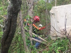 Rescue Squad volunteer descends down steep bluff with aid of a rope to crash site. Note concrete barrier where the 2016 Ford Escape, driven by 62 year old Bryan Boring, went over before overturning down the bluff near the lake