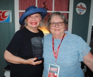 The Smithville Community Chorus delivered a stirring patriotic performance and a tribute to bluegrass during the Fiddlers’ Jamboree Friday evening. Near the end of the show, Faye Fuqua, who founded and has led the chorus since the 1970s was honored by the Jamboree Board. Fuqua’s daughter Kim Luton, President of the Fiddlers Jamboree presented her mother a plaque in appreciation.