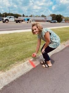 Elise Driver of Coordinated School Health Program pours red sand into the cracks of a sidewalk as part of Red Sand Awareness Project to show how human trafficking survivors have fallen into the cracks in society.