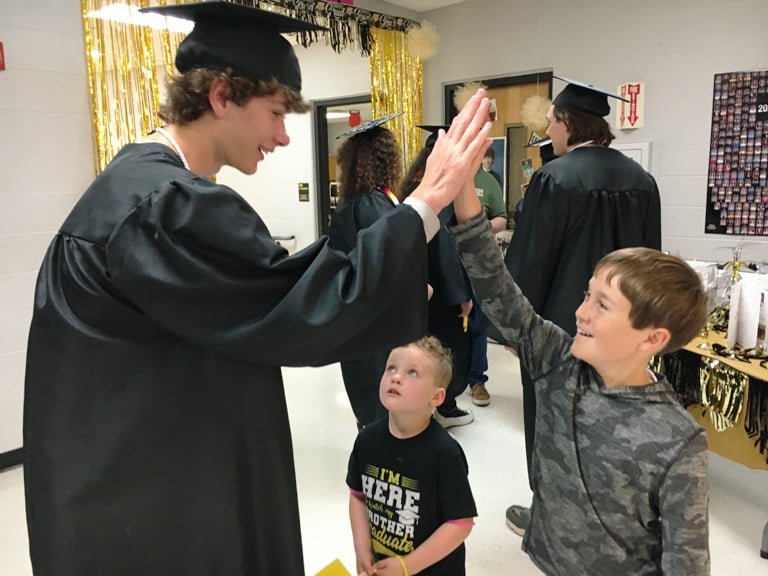 DCHS Senior Marshall Farler gives high five to 5th grader Cainnan Humphrey with Pre-K student Anderson Sliger looking on during the DCHS Class of 2024 Senior Walk at DeKalb West School