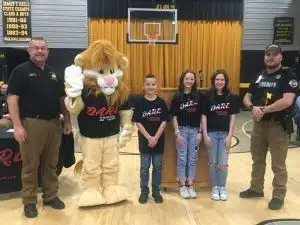 DeKalb West School D.A.R.E. students graduated from the program Friday (January 31) in a special ceremony that was coordinated by SRO Officer Billy Tiner. Pictured left to right: Sheriff Patrick Ray, D.A.R.E. Mascot DAREN the Lion, D.A.R.E. sixth grade essay class winners Jace Davis, Bradi Turney, overall essay winner Paisley Avera, and SRO Officer Billy Tiner