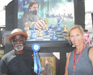 Fiddlers Jamboree Craft Director Judith Hale presents “Best of Show” Craft Award to Gregory Newson of Conway, South Carolina for his art work including paintings many of which focus on historical figures and subject matter